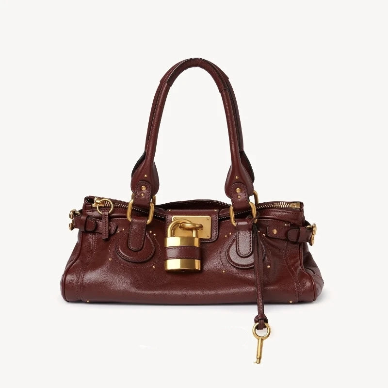 Brown leather handbag with gold accents on a white background