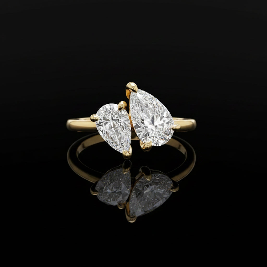 Gold ring with two pear-shaped diamonds on a white background