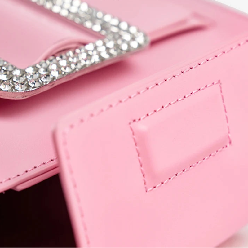 Close-up of a pink handbag with decorative chain