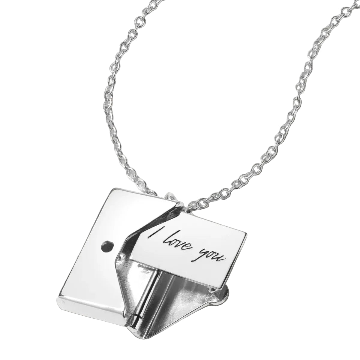 Necklace with a small book-shaped pendant and 'I love you' card on a black background