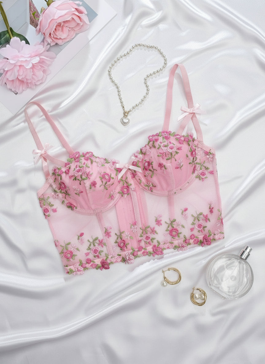 Pink floral bralette with matching top on a white surface with flowers and jewelry.