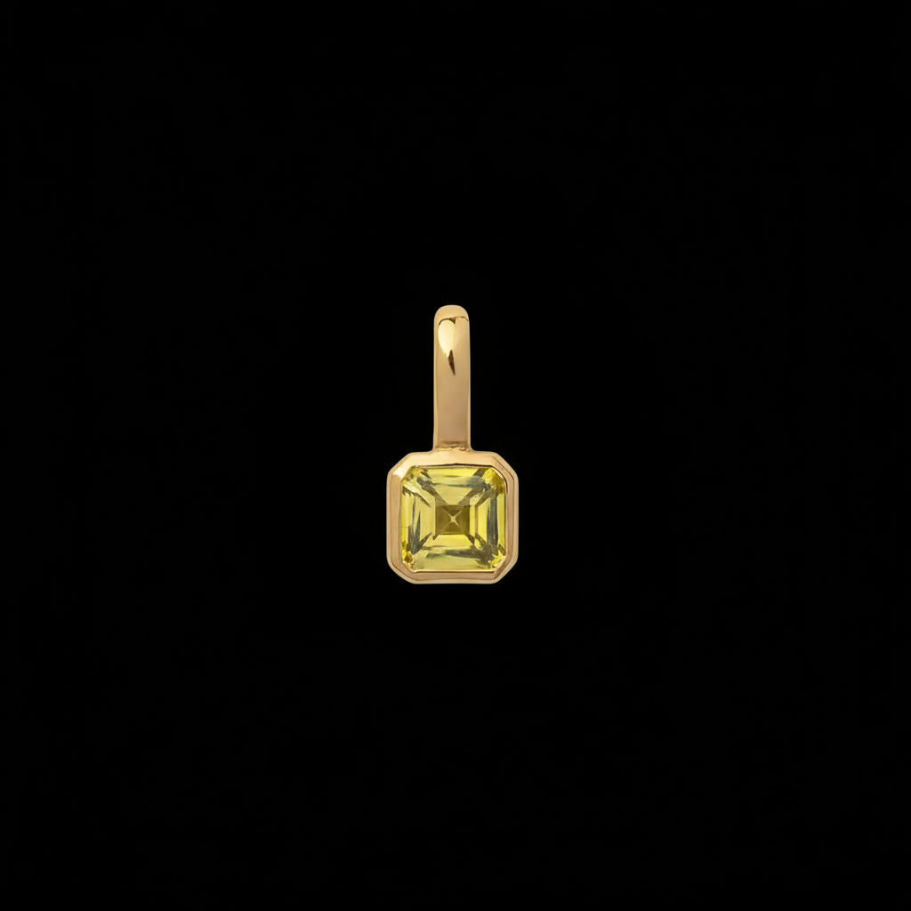 Gold pendant with a green gemstone on a beige background